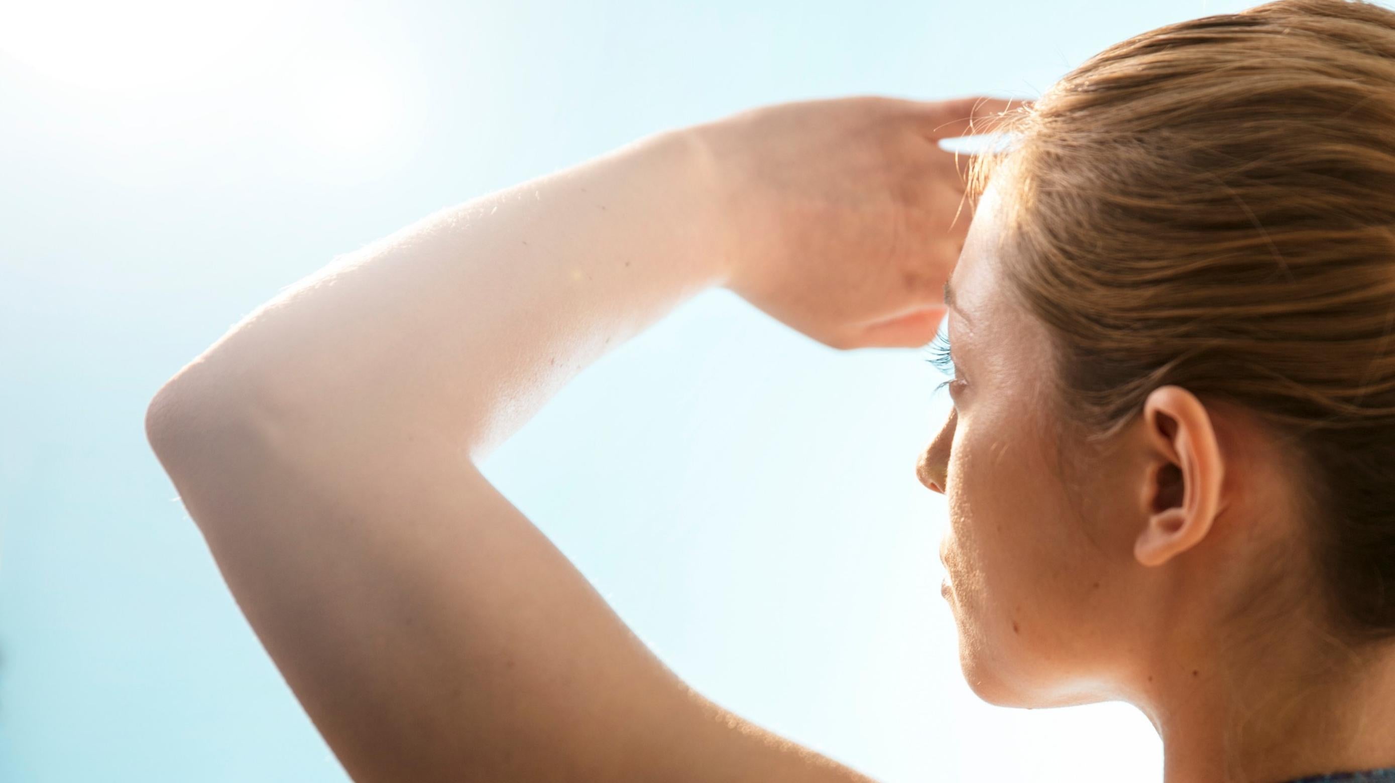woman staring into sun covering eyes