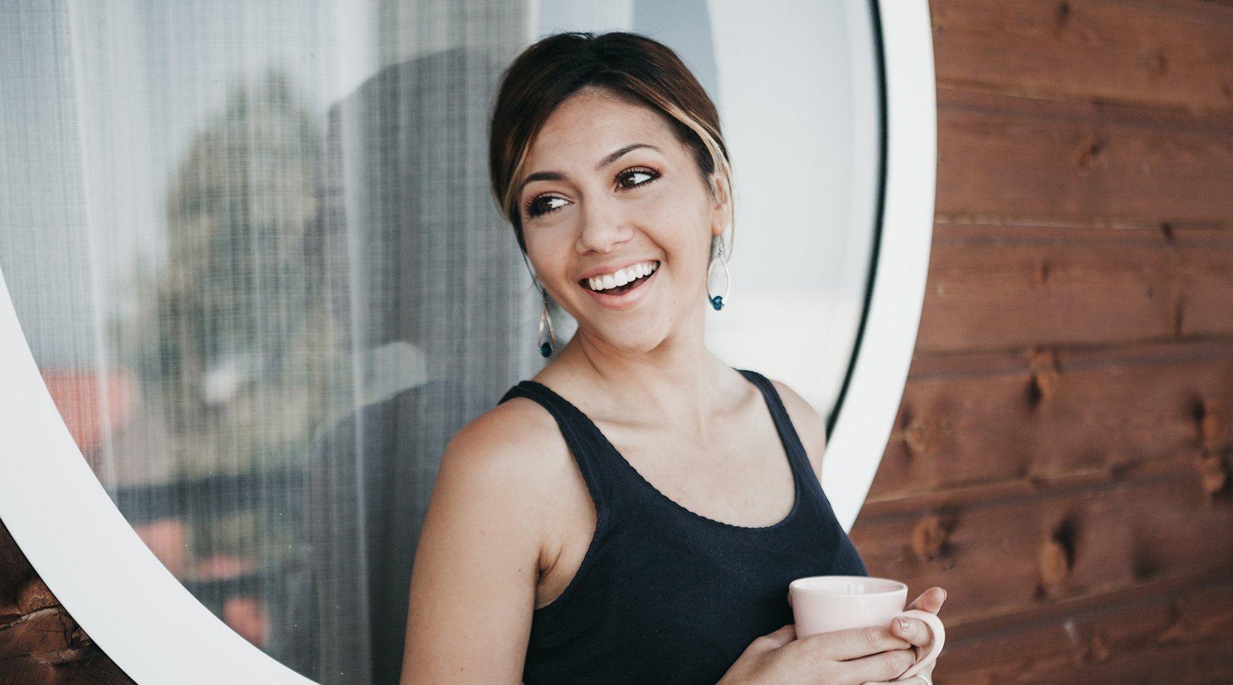 Woman holding coffee and smiling