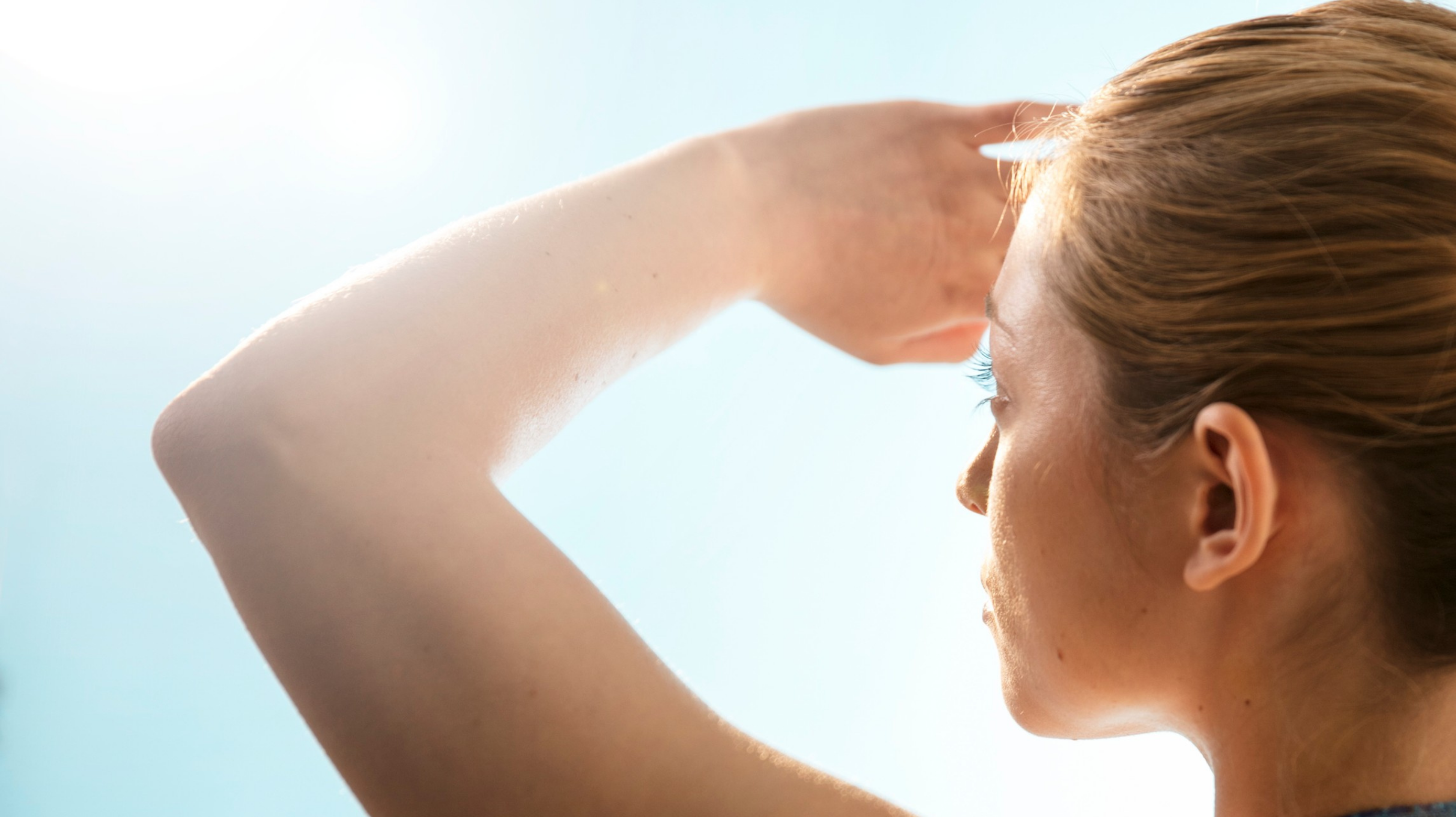 woman staring into sun covering eyes