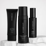 Three black skincare bottles from withSimplicity are arranged on white stone blocks against a light gray background. The products include Face Lotion, Foaming Face Wash, and Toner.