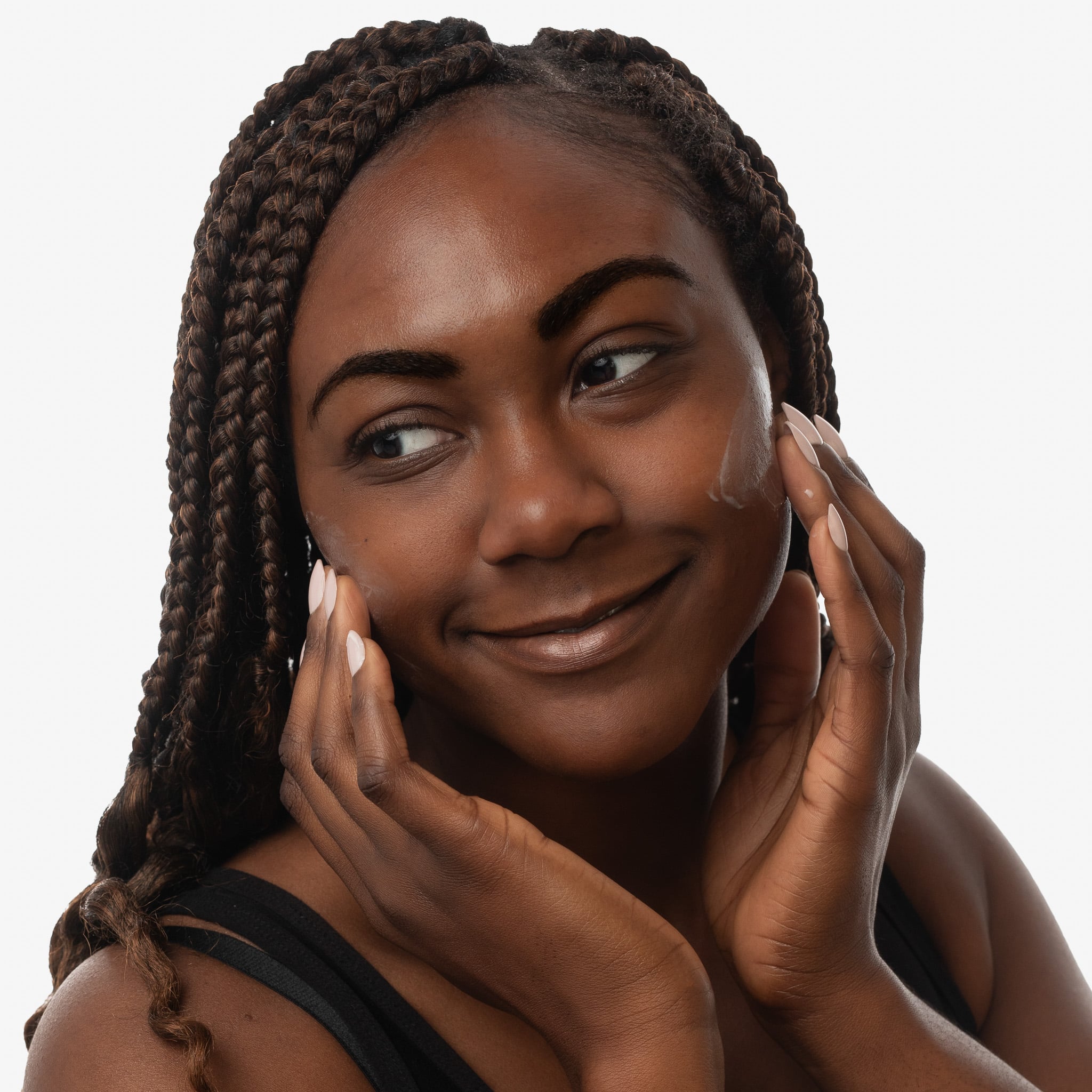 Woman applying skincare product to her face on a plain background