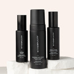 Three withSimplicity acne-prone skincare products—one toner bottle, one lotion bottle, and a foaming face wash—arranged on stone with soft beige background.