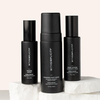 Three withSimplicity acne-prone skincare products—one toner bottle, one lotion bottle, and a foaming face wash—arranged on stone with soft beige background.