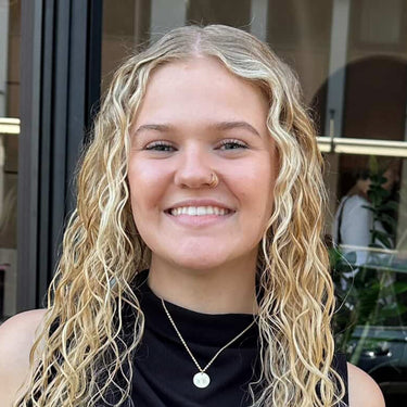 Woman with long blonde hair smiling outdoors