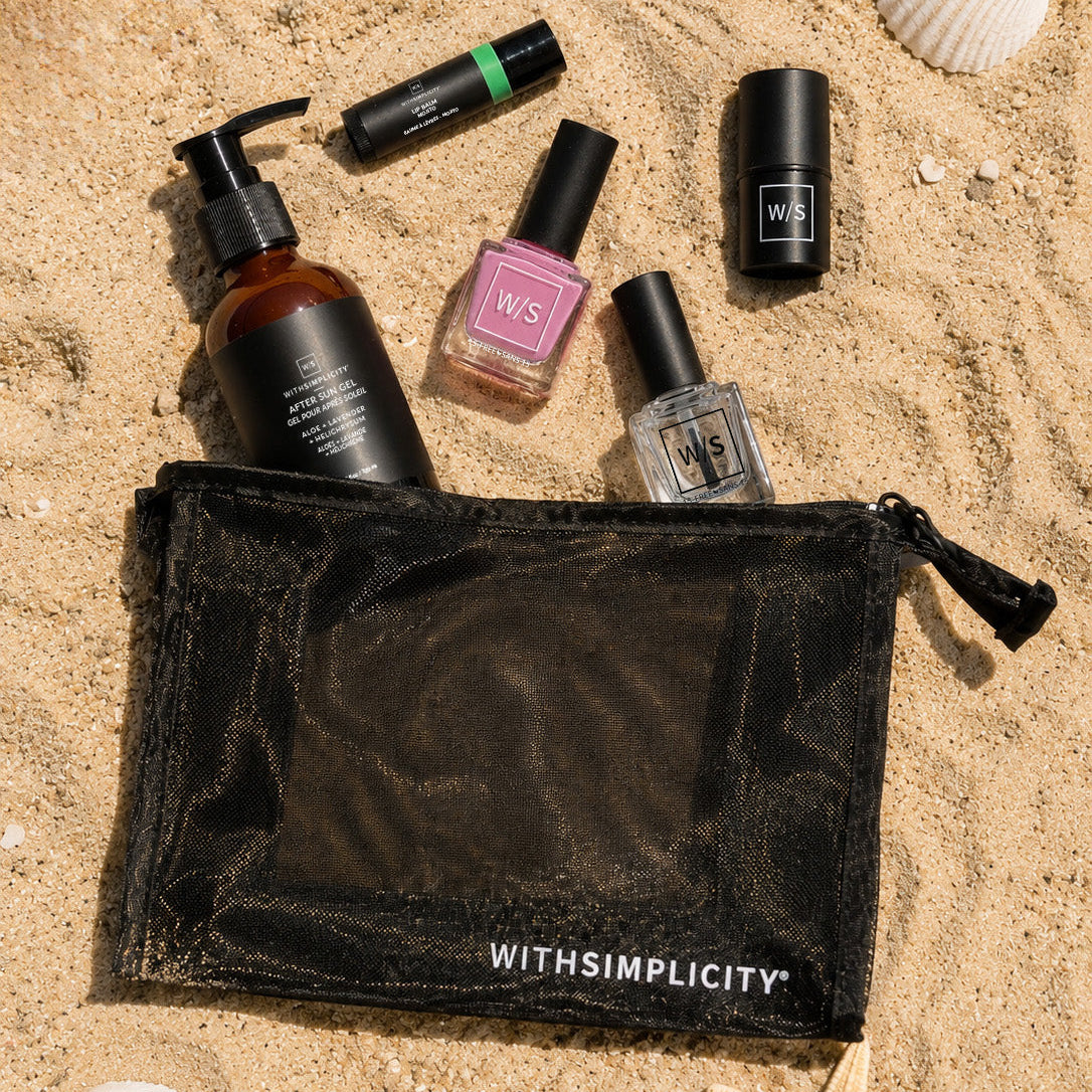 Set of beauty products including bottles and a pouch on sand with shells and starfish.