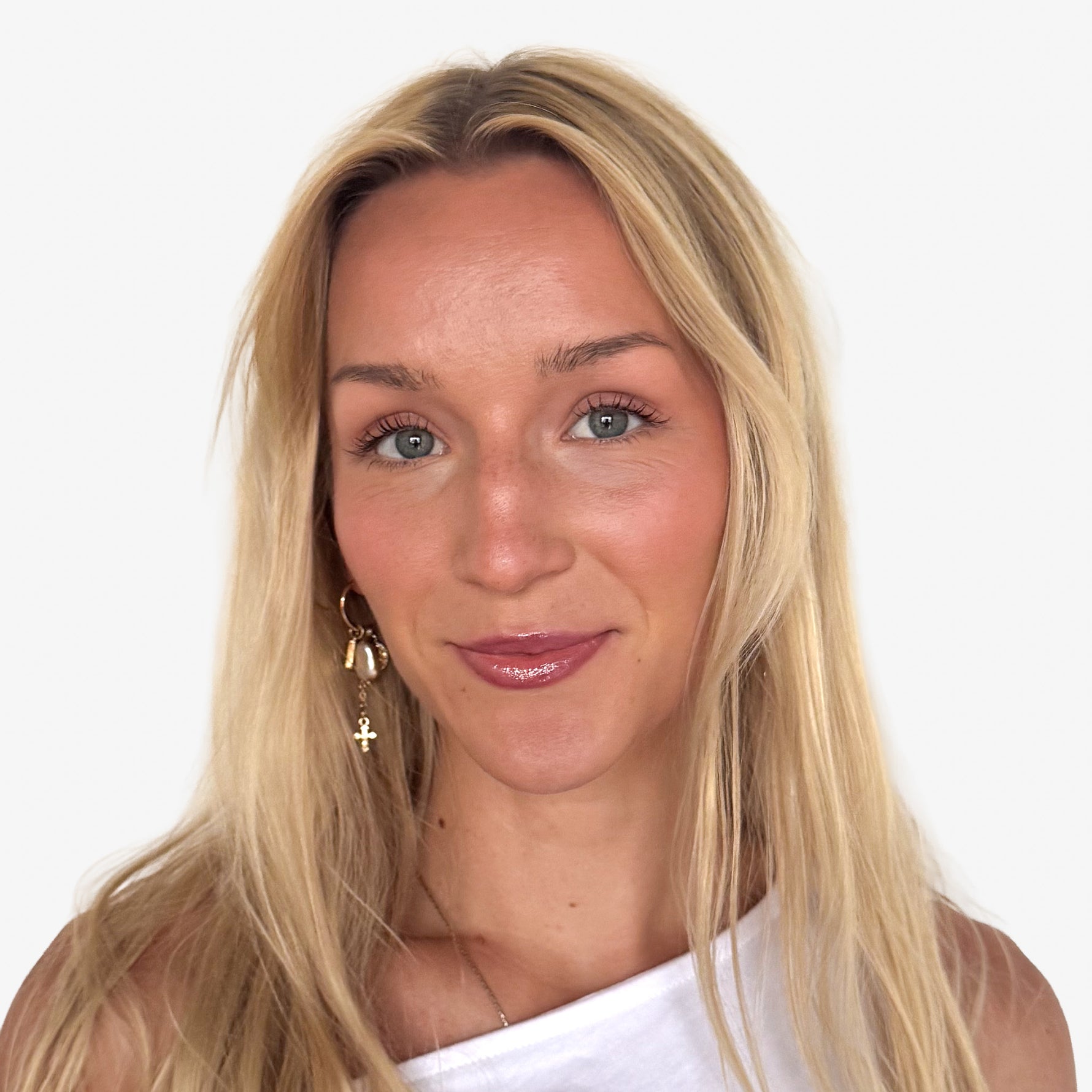Woman with blonde hair and a white top against a plain background