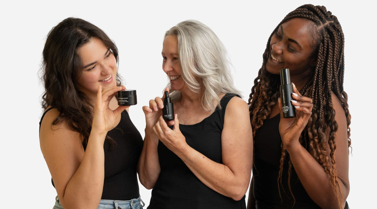 Three women holding black cylindrical products against a white background