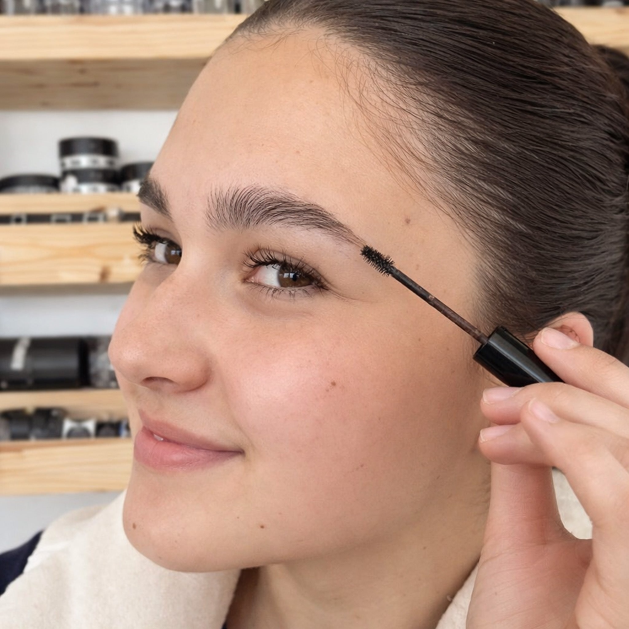 Woman applying brow gel to eyebrows with applicator wand