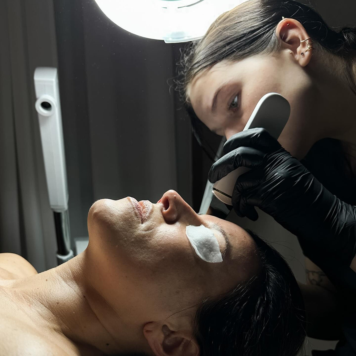 Person receiving a facial treatment with a professional in a clinical setting.