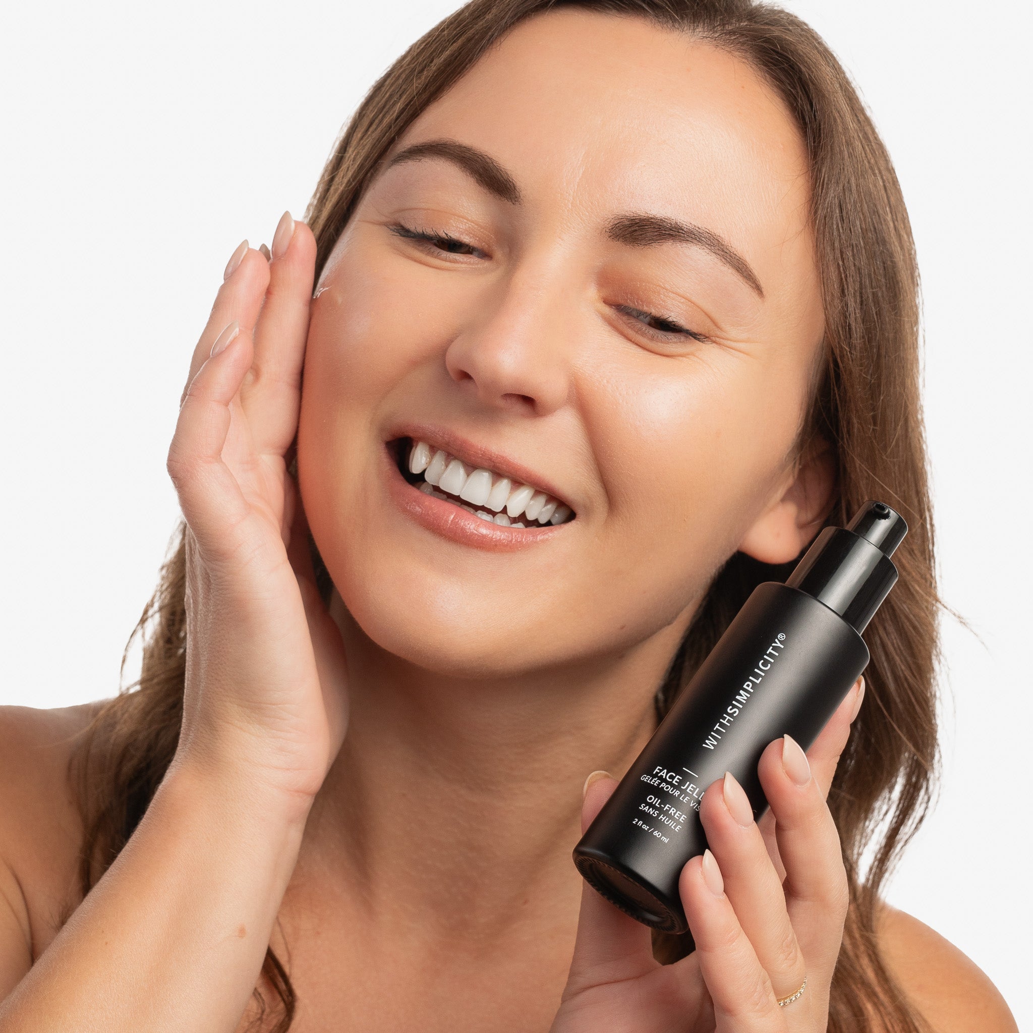 Woman applying skincare product to face with a neutral background
