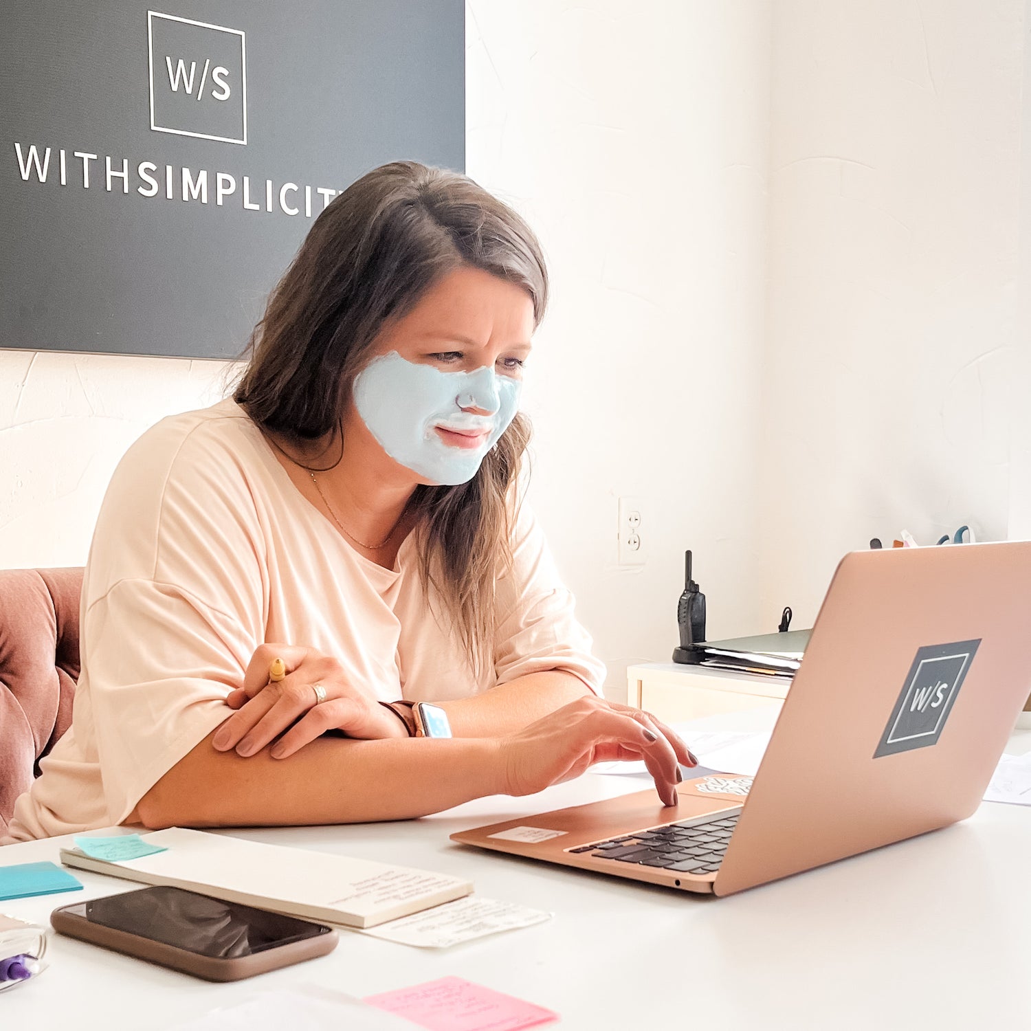 woman sitting at computer at desk with a skincare face mask on her face