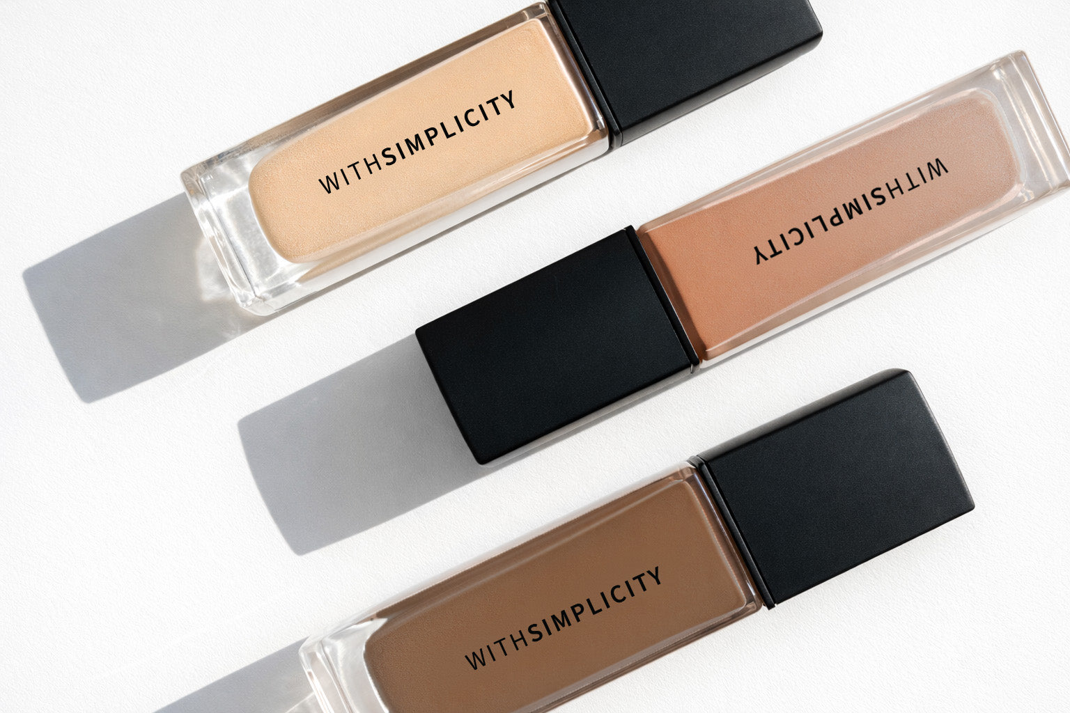 Three concealer tubes with 'WITH SIMPLICITY' branding on a white background
