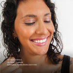 Close-up of a woman with makeup products listed on a white background. Products listed are Tri-Stick Valencia, Lip gloss Coquette, Eyeshadow Creme Brulee