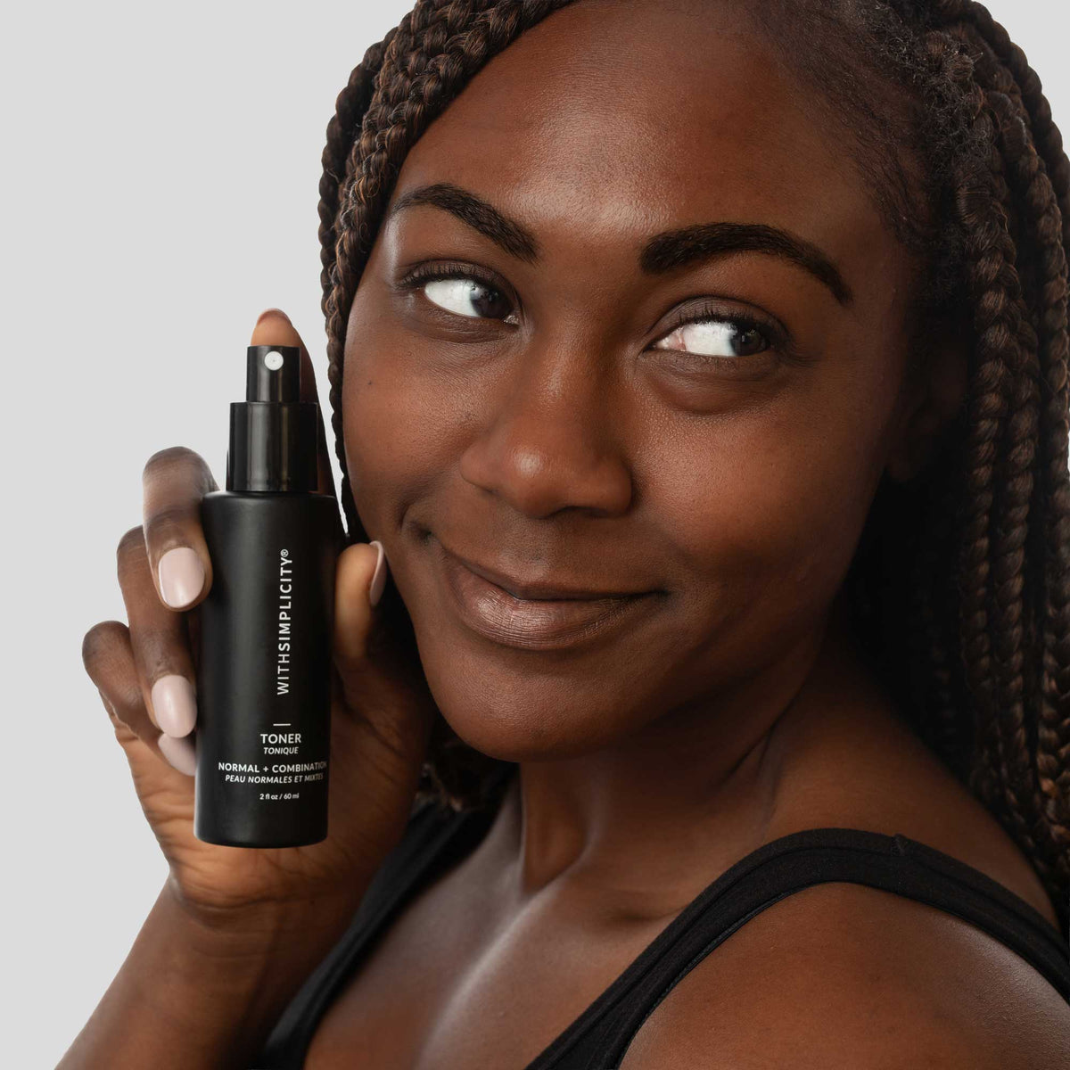 woman holding withSimplicity Normal Combo Toner in hand by face against a light gray background