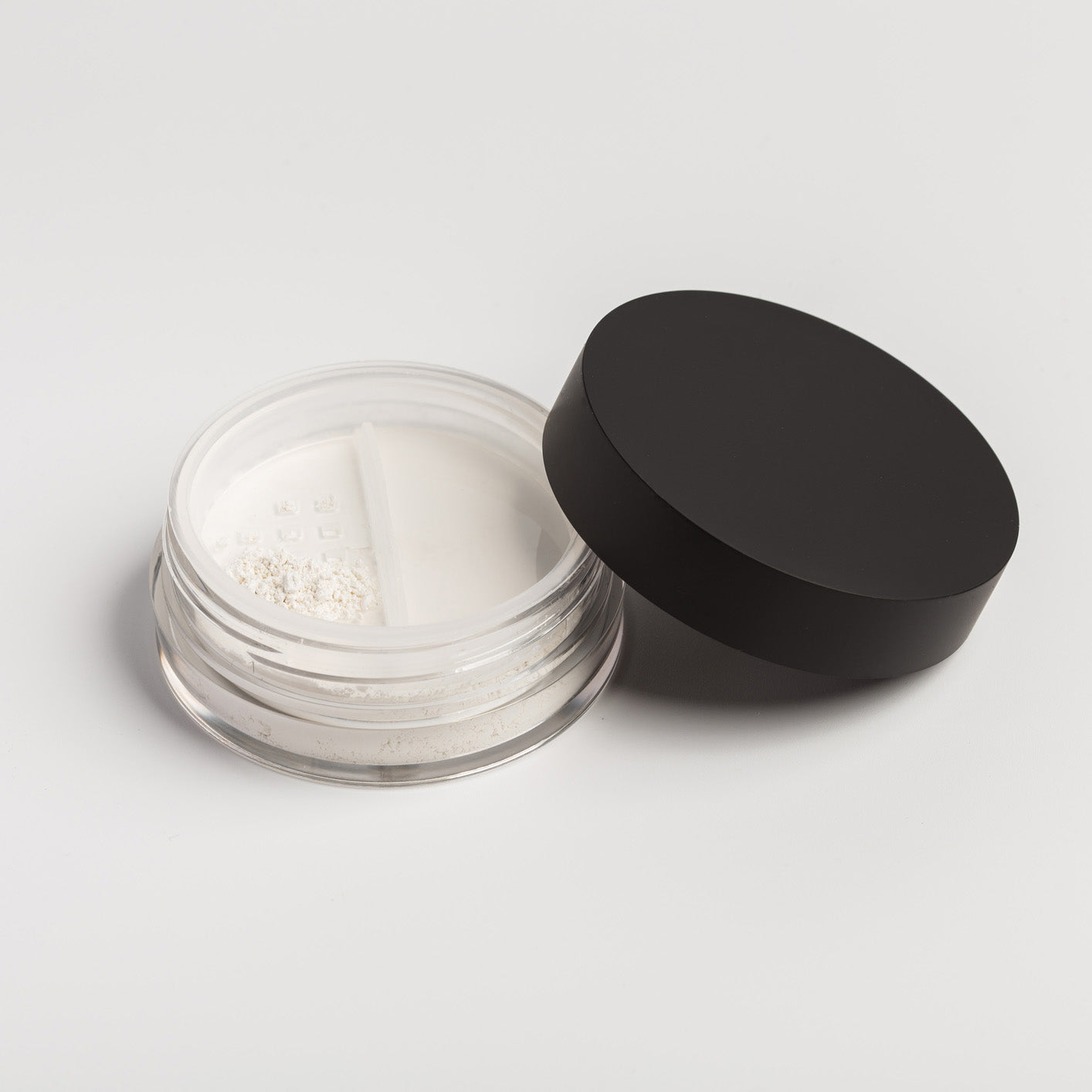Open jar of white powder with a black lid on a light gray background