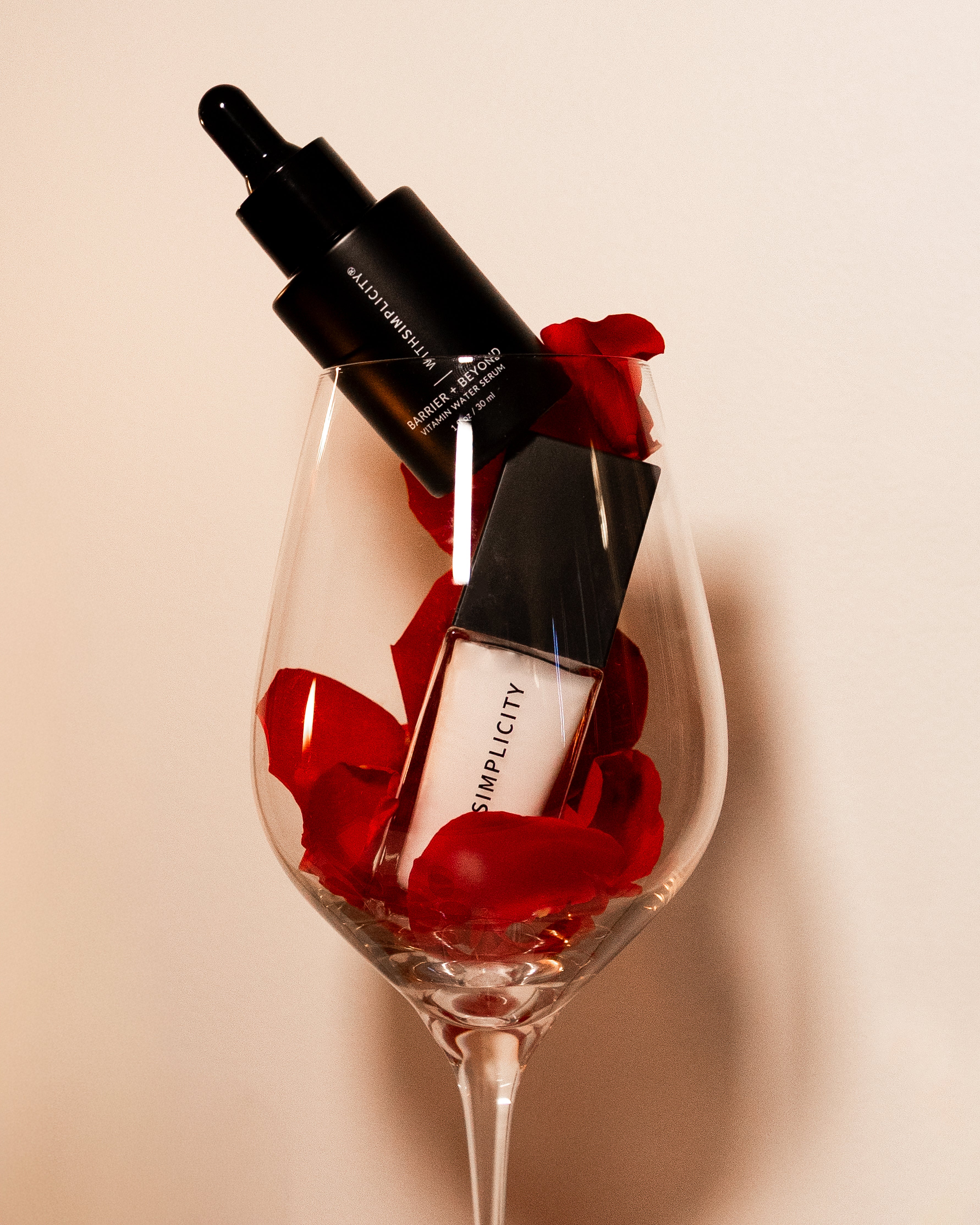 withSimplicity Barrier & Beyond Serum and Face Primer in a wine glass with red flowers on a beige background