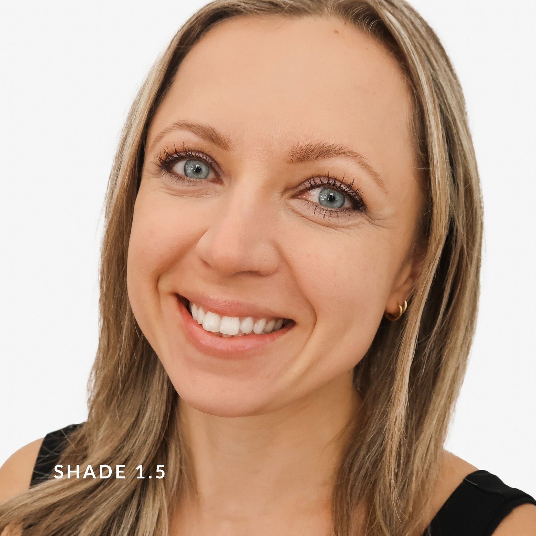 Close-up of a woman with blonde hair and blue eyes on a white background. Says Shade 1.5