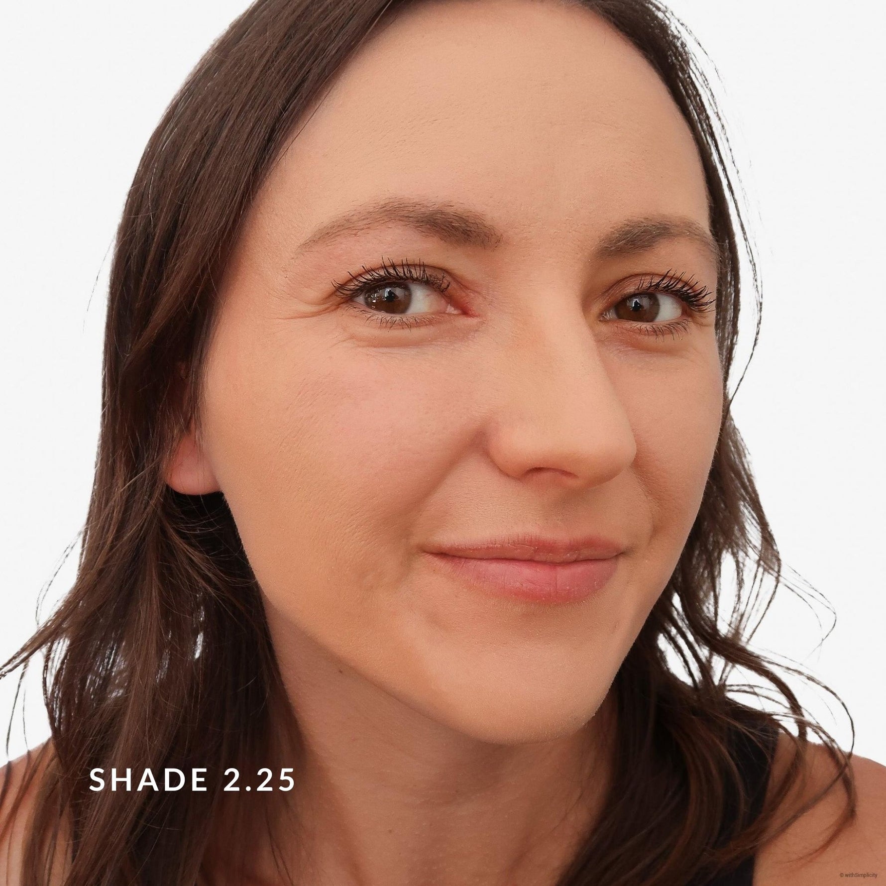 Close-up of a woman's face with brown hair and brown eyes, wearing makeup, on a white background. Says Shade 2.25