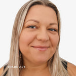 Woman with blonde hair and blue eyes on a white background, wearing a black top. Says shade 2.75