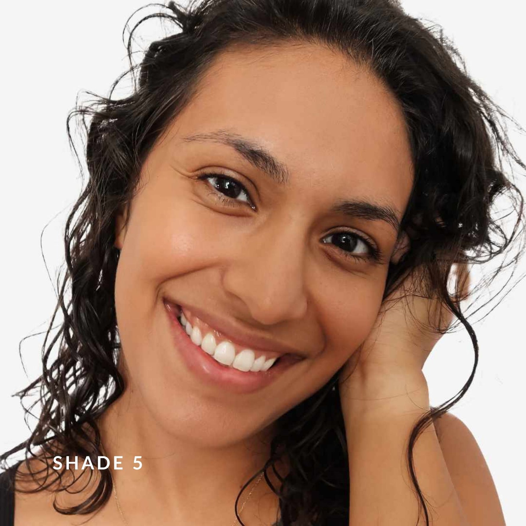 Woman with dark hair smiling on a plain background. Text says Shade 5