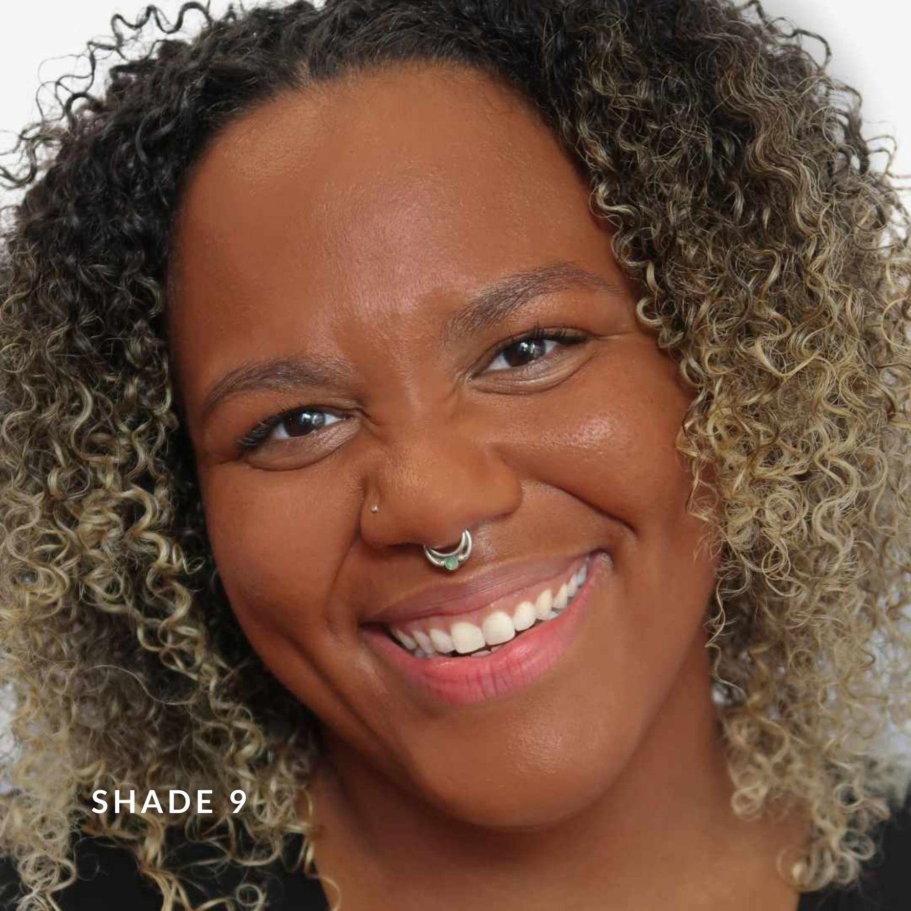Woman with curly hair smiling, wearing a nose ring, with 'Shade 9' text.