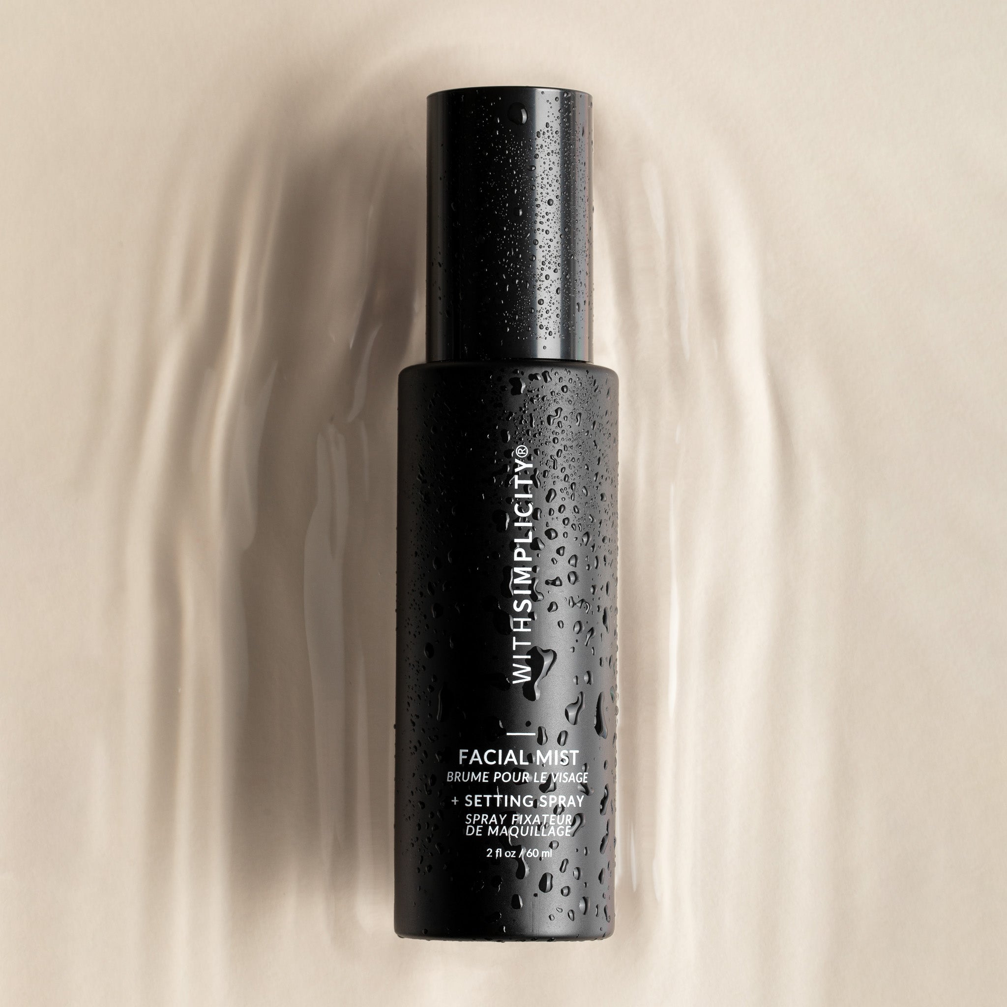 Black withSimplicity facial mist bottle with droplets on a beige background